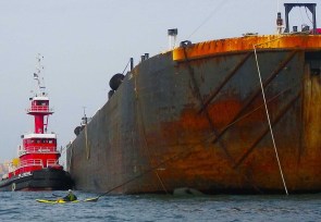 Passing in front of a rusty barge in the Bay Ridge Anchorage