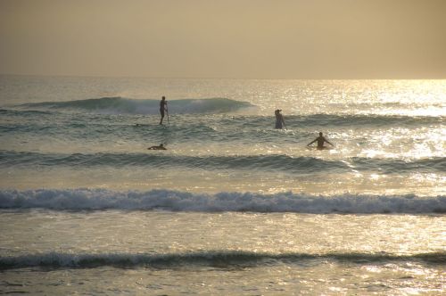 Figures in waves at dawn